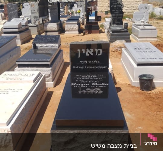 מצבות שחורות ולבנות בבית קברות תחת שמיים כחולים
